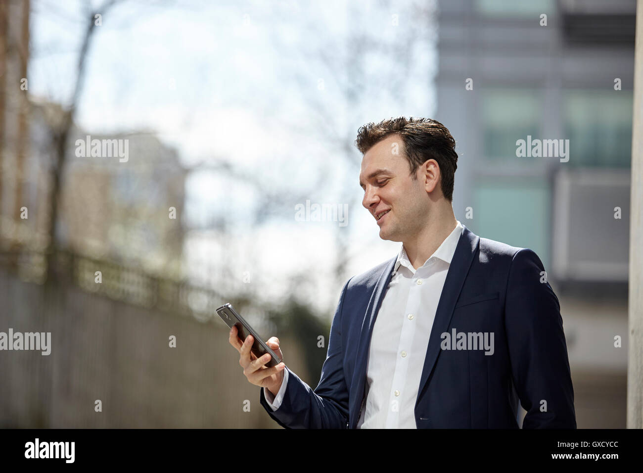 Geschäftsmann lesen Smartphone Texte außerhalb Büro, London, UK Stockfoto