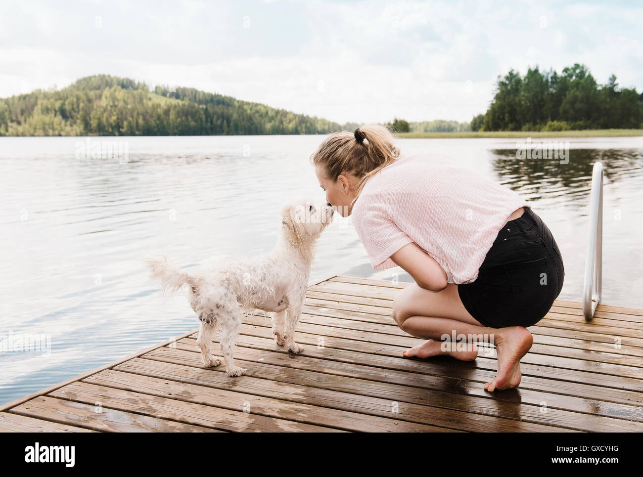 Frau küssen Coton de Tulear Hund auf Pier, Orivesi, Finnland Stockfoto