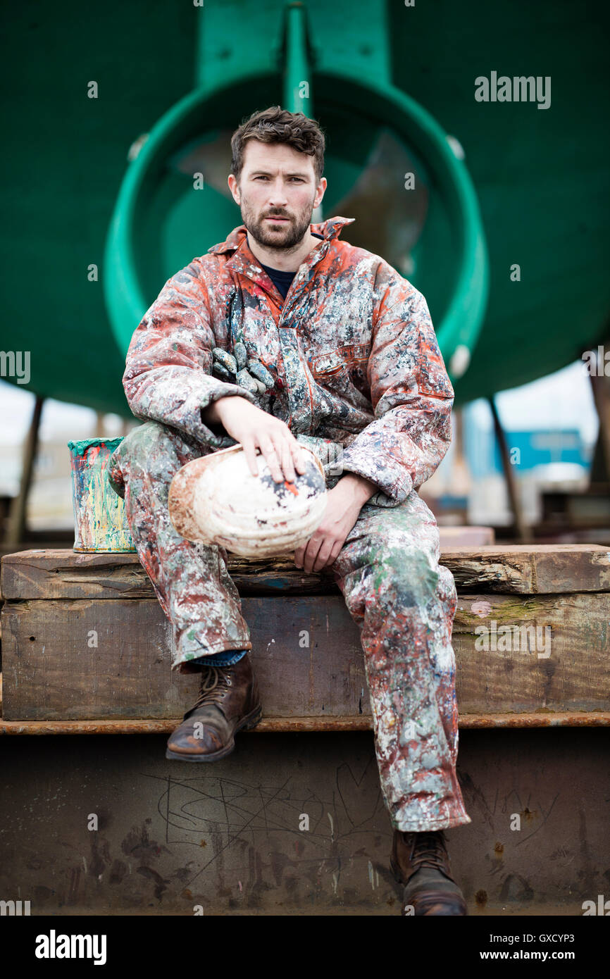 Porträt von männlichen Schiff Maler sitzen vor grünen Schiffsrumpf Stockfoto