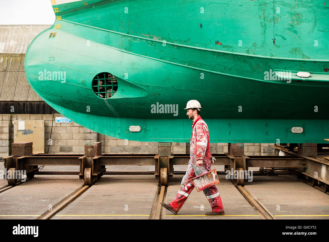 Männliche Schiff Maler tragen Farbdosen in Werft Maler Stockfoto