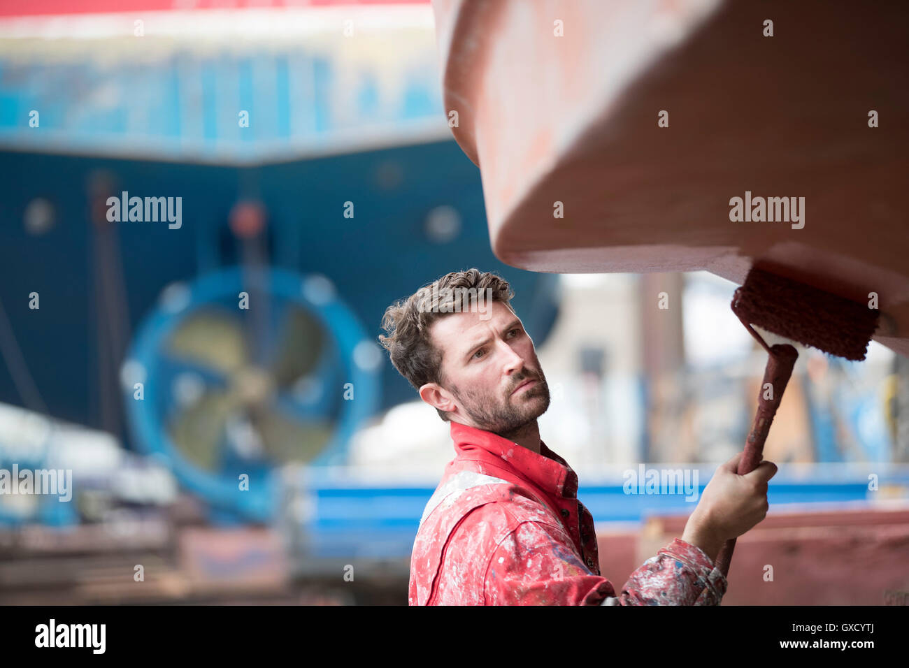 Männliche Schiff Maler Walze Malerei Schiffsrumpf in Werft Maler Stockfoto
