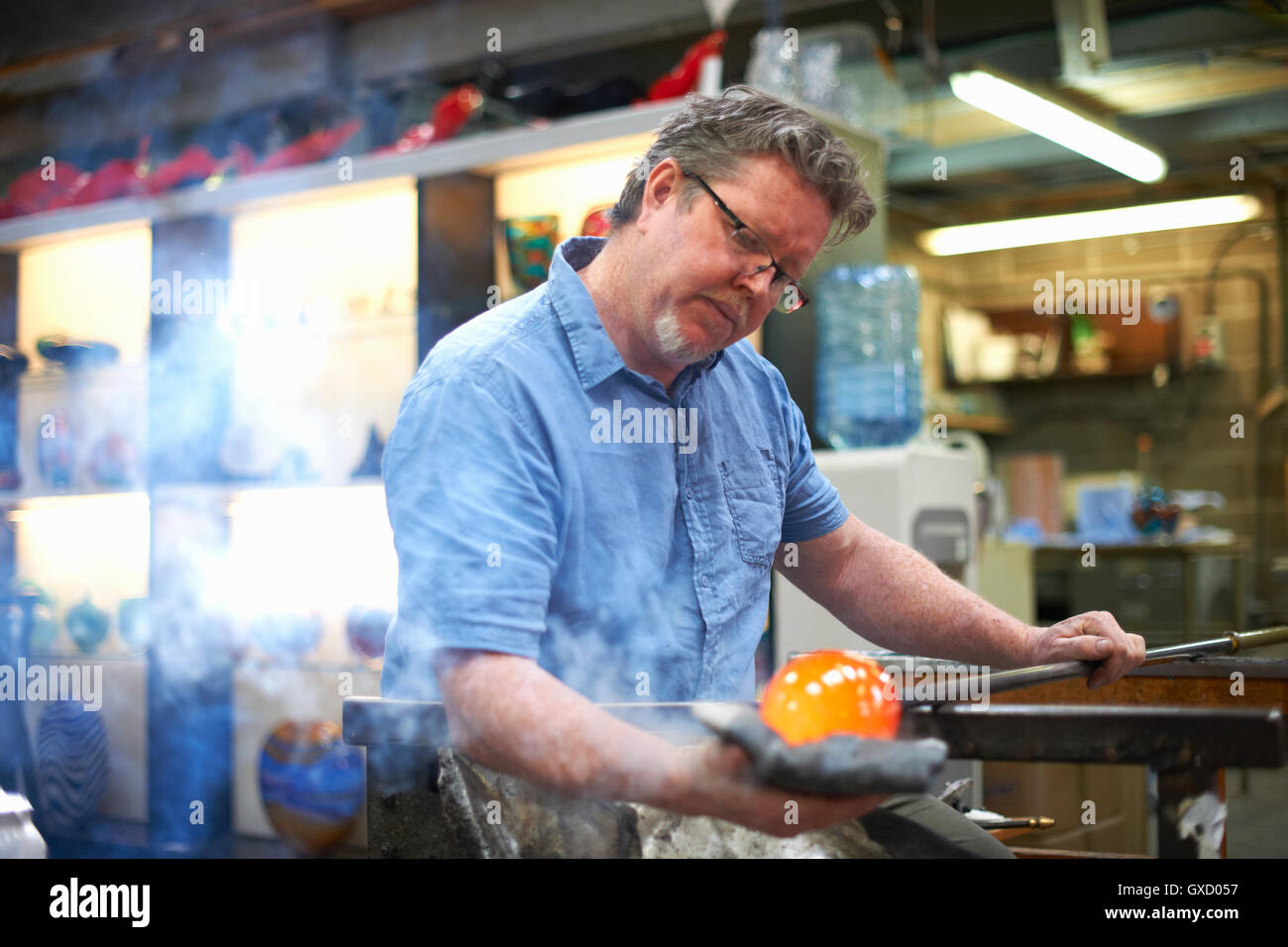 Glasbläser in Werkstatt bilden geschmolzenes Glas auf Blasrohr Stockfoto