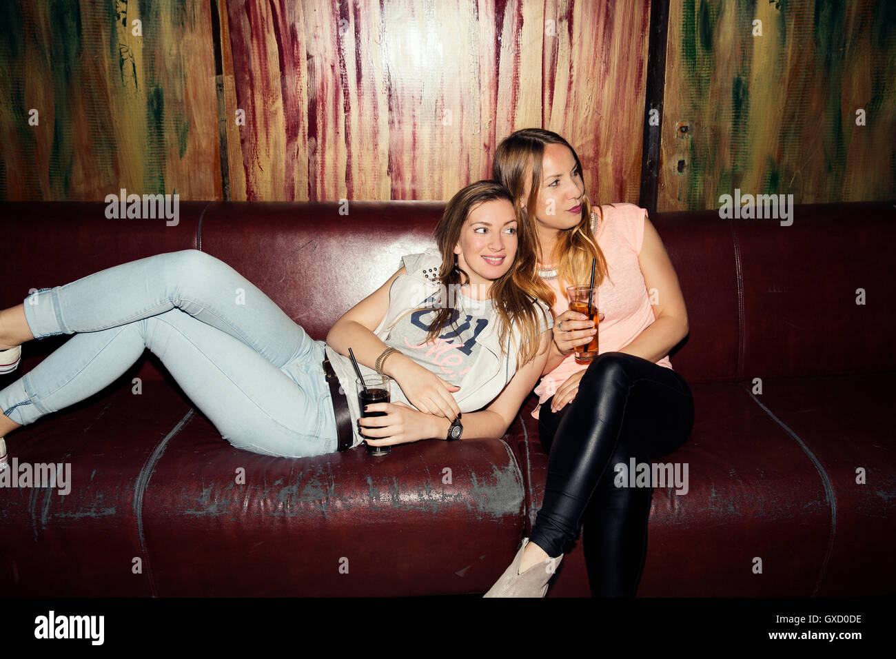 Zwei Erwachsene Freundinnen auf Sofa zurückgelehnt auf ausgehen in bar Stockfoto