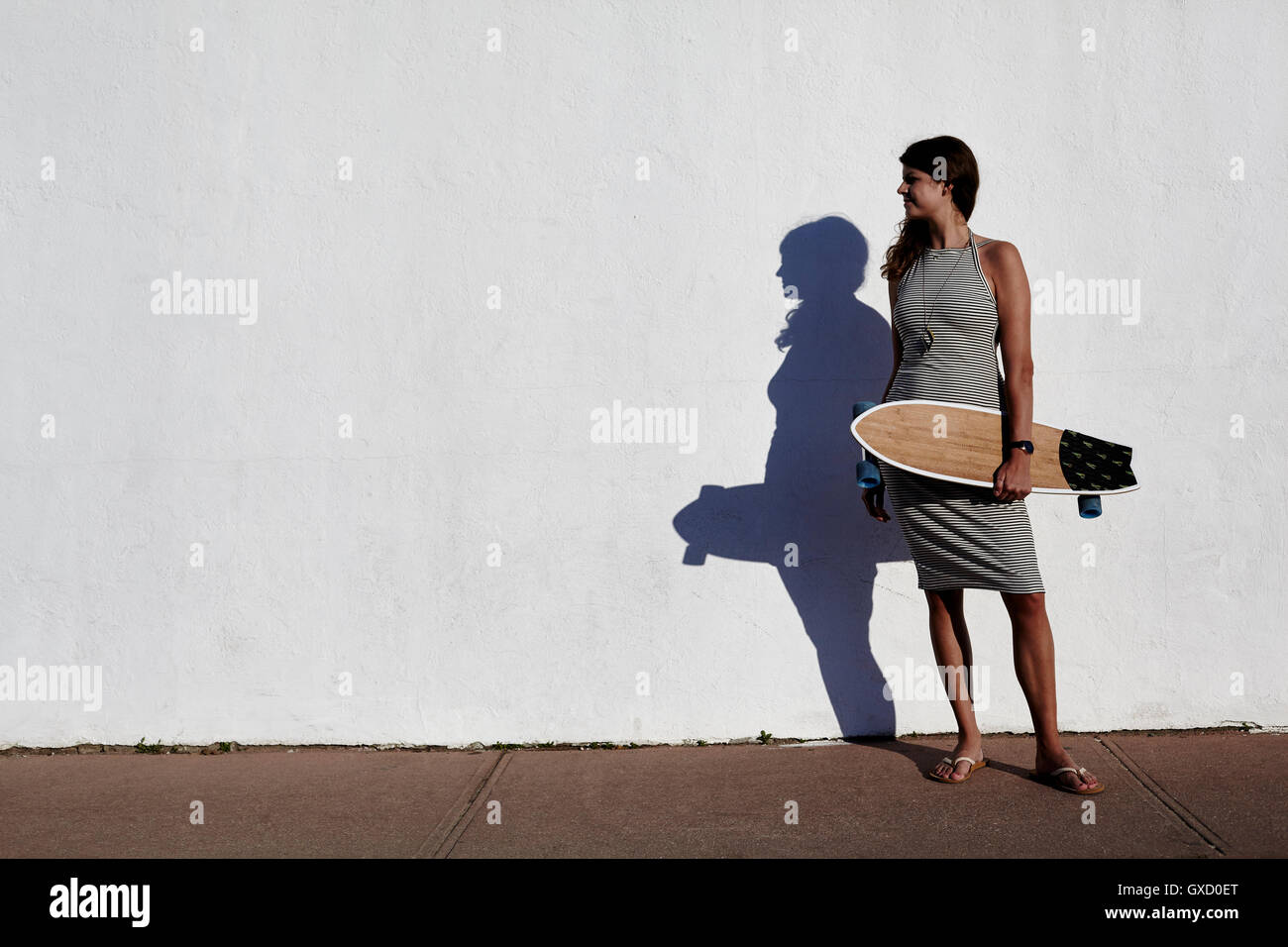 Coole junge Frau stand vor der weißen Wand mit Skateboard, New York, USA Stockfoto