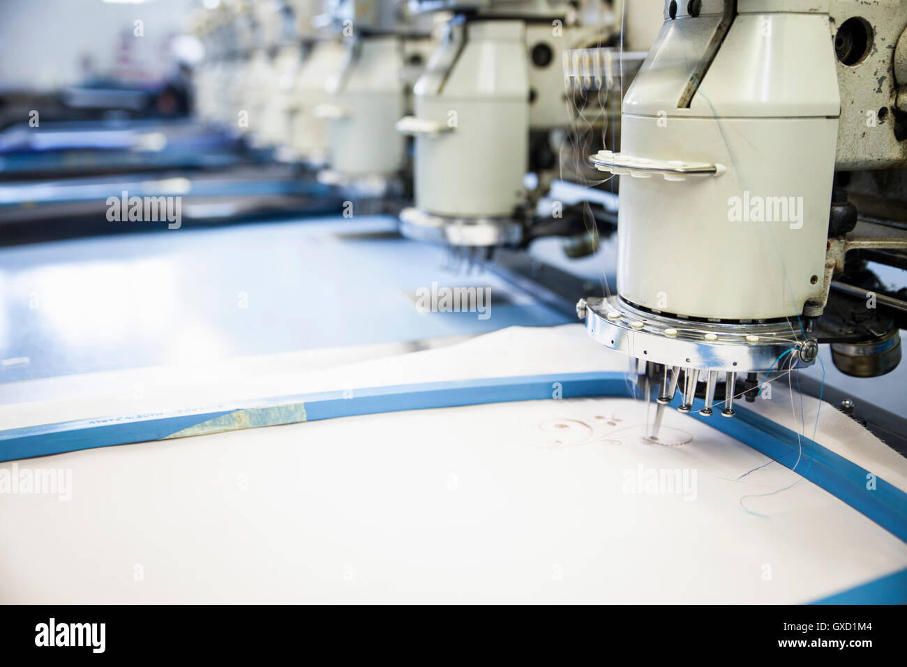 Reihen von programmierten Stickmaschinen Geschwindigkeit Nähte weißes Tuch in Kleiderfabrik Stockfoto