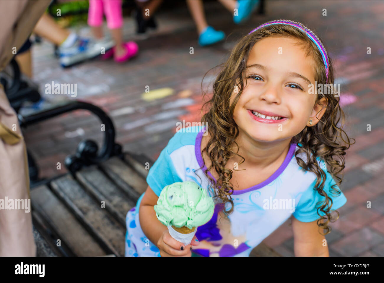 Porträt von netten Mädchen essen Eiscreme-Kegel auf Bürgersteig Stockfoto