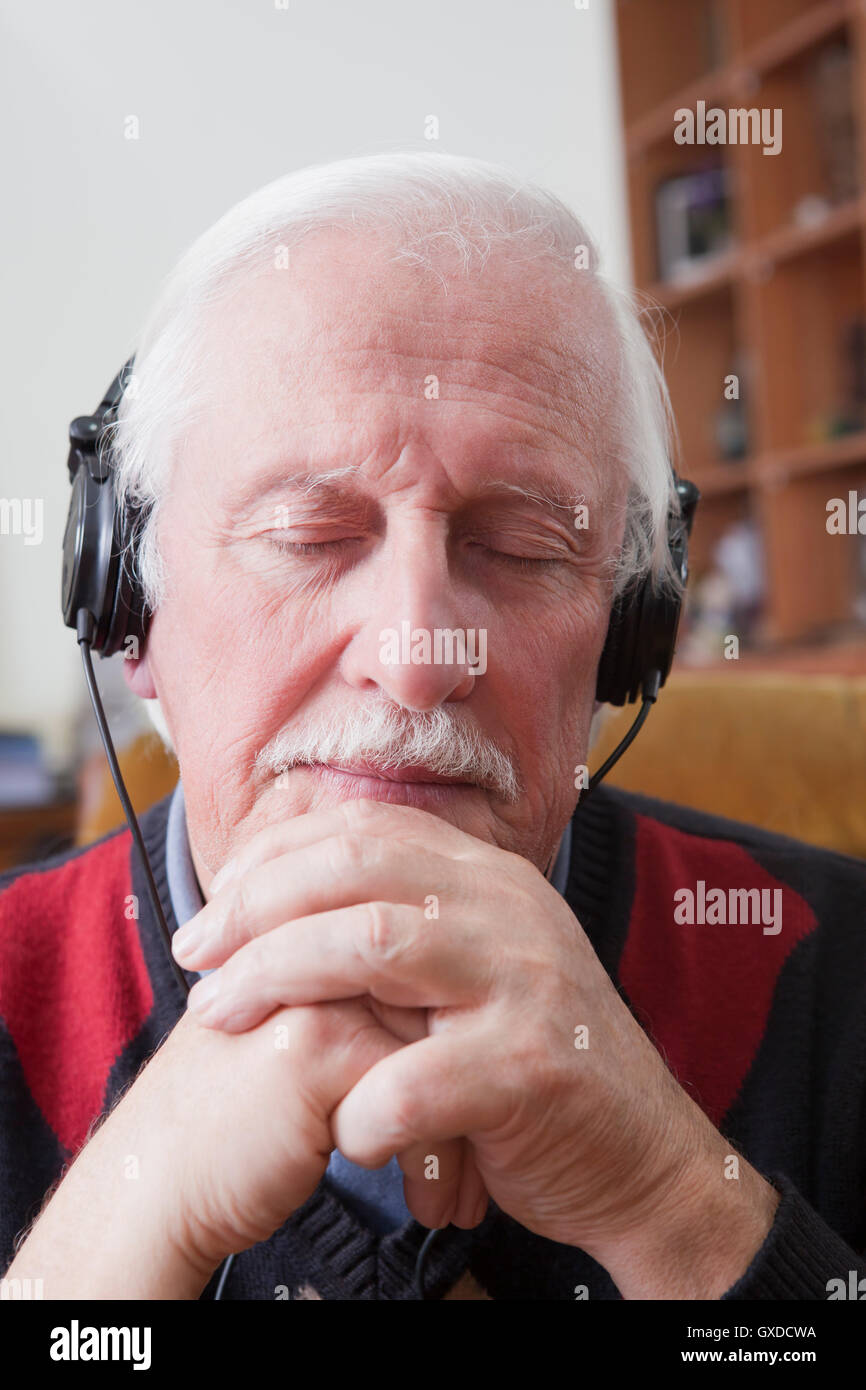 Senior woman anhören von Musik über Kopfhörer zu Hause Stockfoto