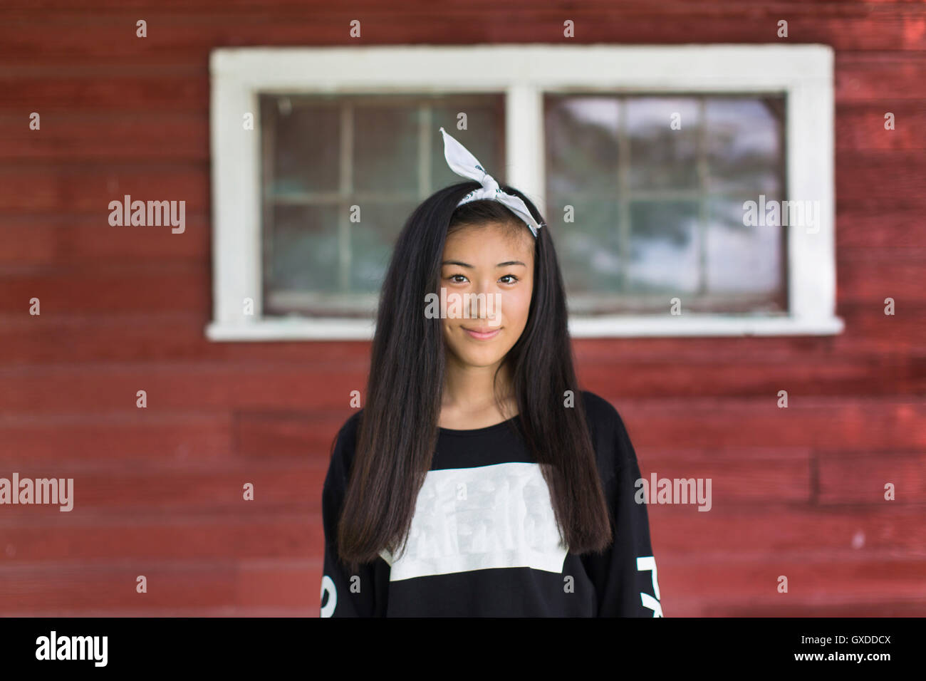 Porträt der lächelnde Teenager-Mädchen mit langen schwarzen Haaren und Haarband in Veranda Stockfoto