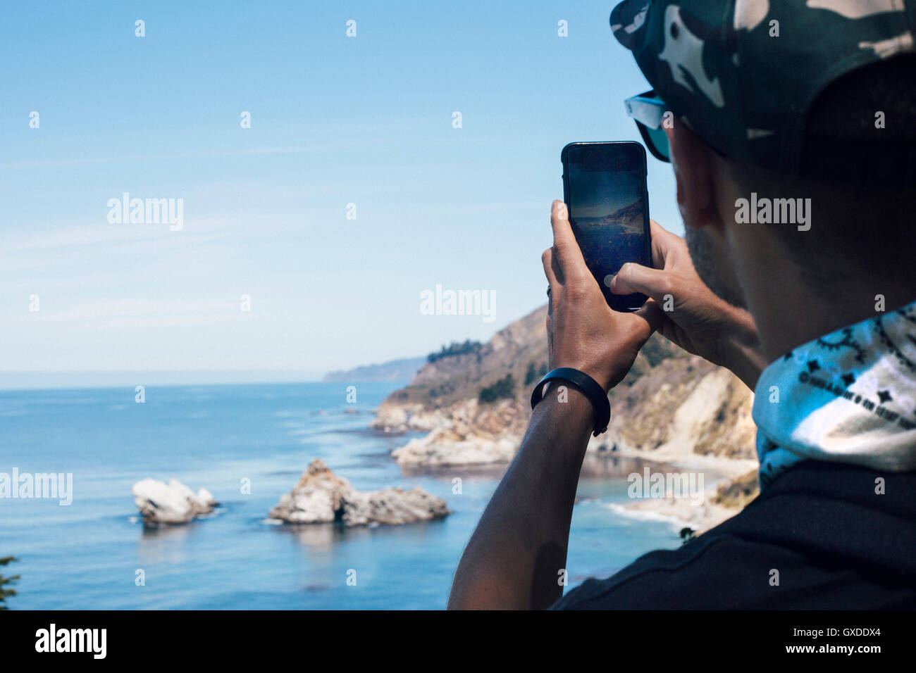 Über Schulter Blick des Menschen fotografieren Küste auf Smartphone, Big Sur, Kalifornien, USA Stockfoto