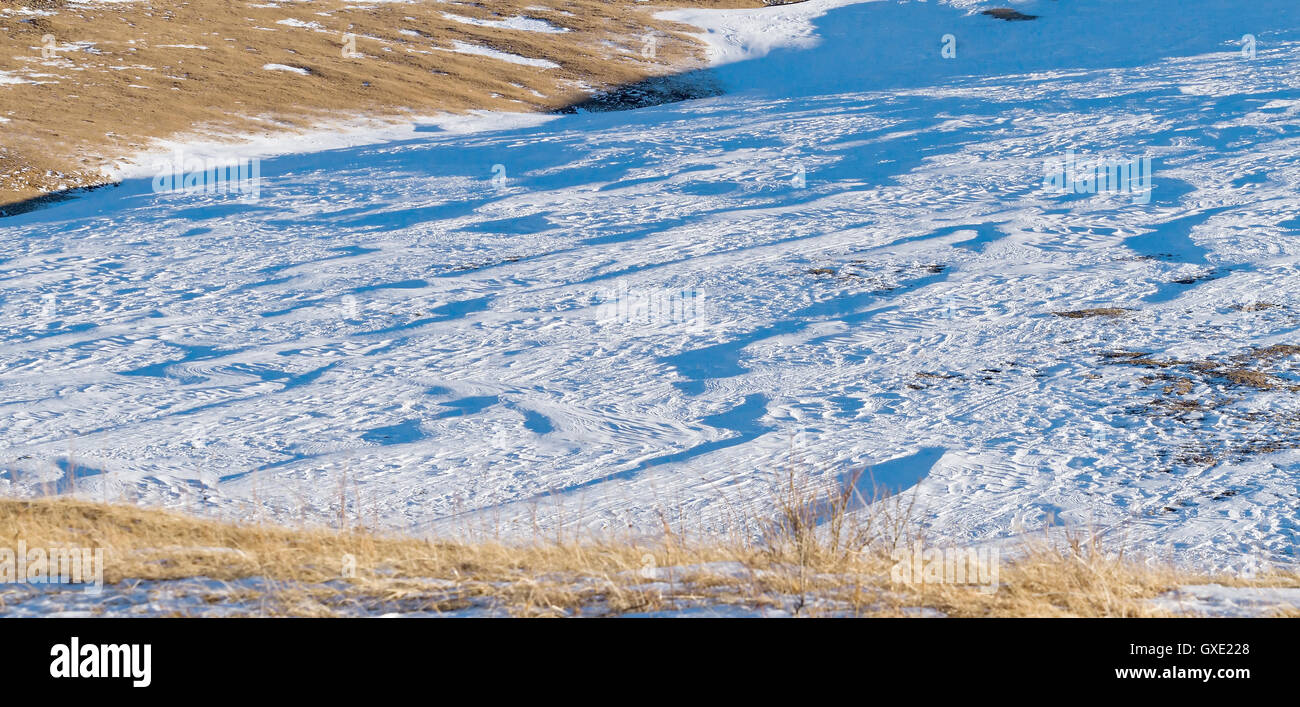 Winter-abstrakt strukturierten Hintergrund / Hintergrund: Berg Abstieg mit Schnee bedeckt und alten trockenen Rasen. Stockfoto