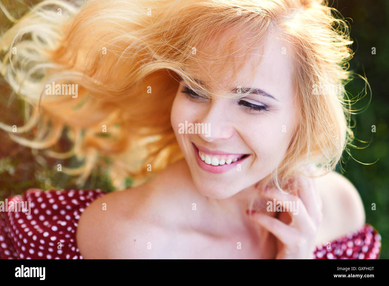 Glücklich lächelnde Frau in einem Park auf dem Rasen Stockfoto