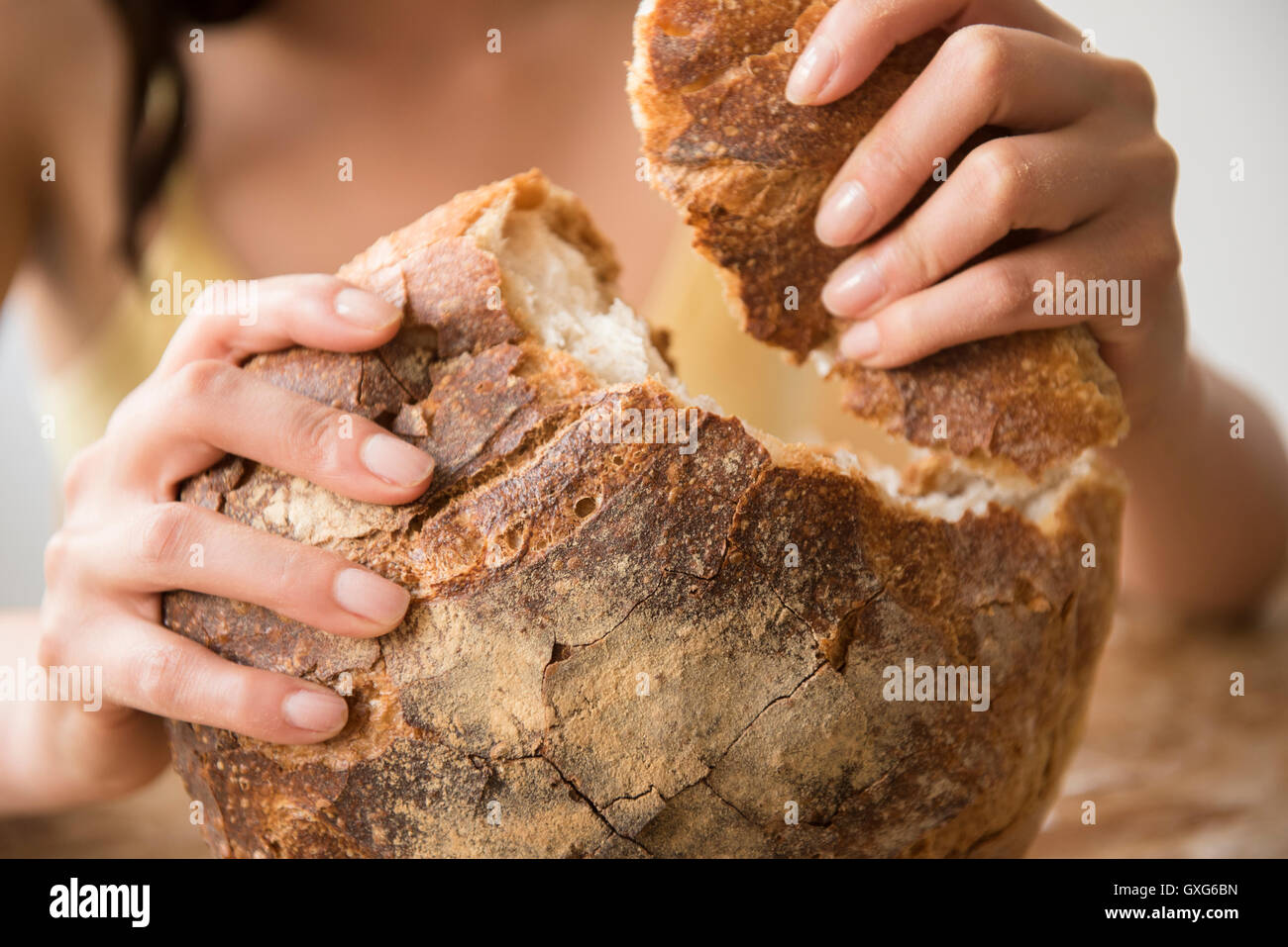 Hispanic Frau reißen rundes Laib Brot Stockfoto