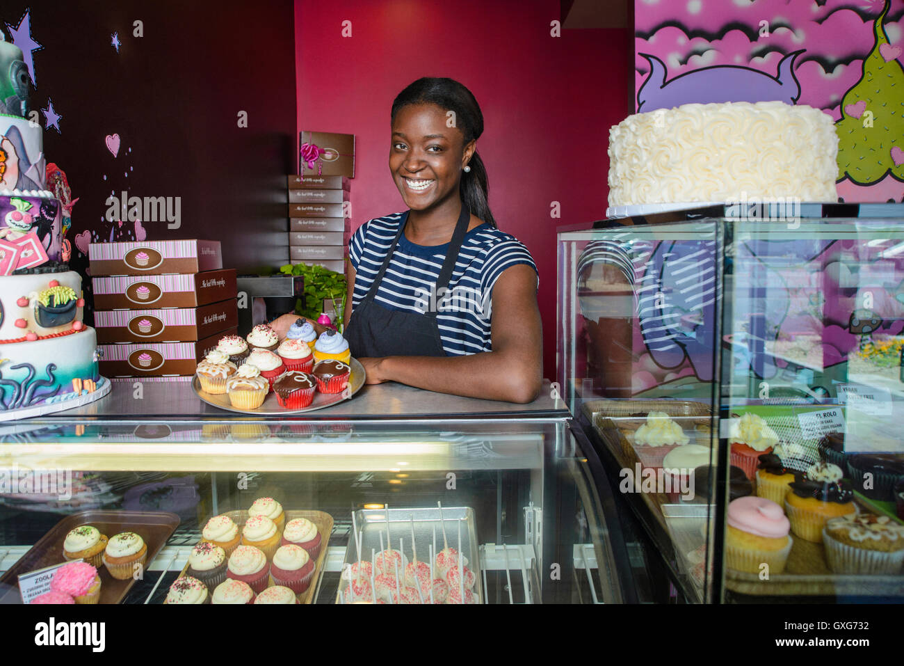 Schwarze Unternehmer zeigen Cupcakes bei Bäckerei Vitrine Stockfoto