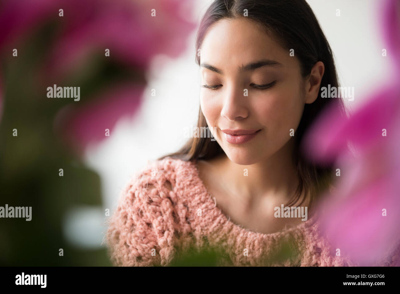 Nachdenklich Hispanic Frau hinter rosa Blüten Stockfoto