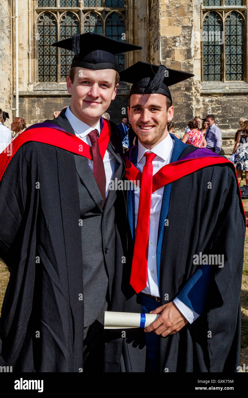 Zwei Hochschulabsolventen posieren für ein Foto vor Canterbury Kathedrale vor ihrer Graduierung Zeremonie, Canterbury, Kent, UK Stockfoto