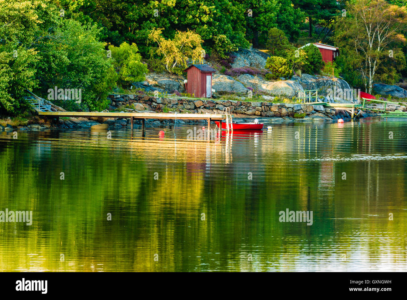 Windstillen Wasser und Holzsteg mit kleinen Boot vertäut daneben. Kleiner Schuppen auf Insel in Herbstlandschaft. Kopieren Sie Platz im Wasser. Stockfoto