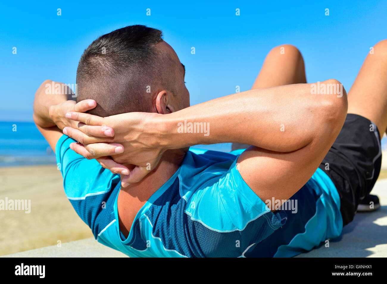 ein junger kaukasischen Sportler Sport Kleidung tut Bauch Übungen im Freien mit seinen Händen in den Nacken und Knie werden Stockfoto