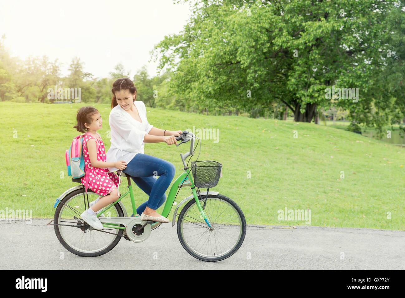 Asiatische Mutter und Tochter Radfahren Fahrrad im Park in der Schule. Mutter und Tochter Radfahren Fahrrad zusammen. Stockfoto