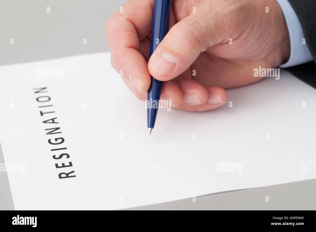 Mann mit einem Stift in der Hand, schreiben einen Brief der Resignation auf einem Tisch Stockfoto