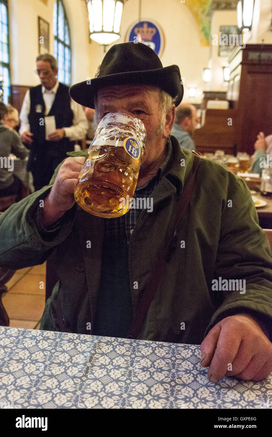 Einheimischen kann gesehen gekleidet in traditioneller Tracht, Münchner Bier aus der berühmten Masse, eine 1-Liter-Krug, trinken und genießen Stockfoto