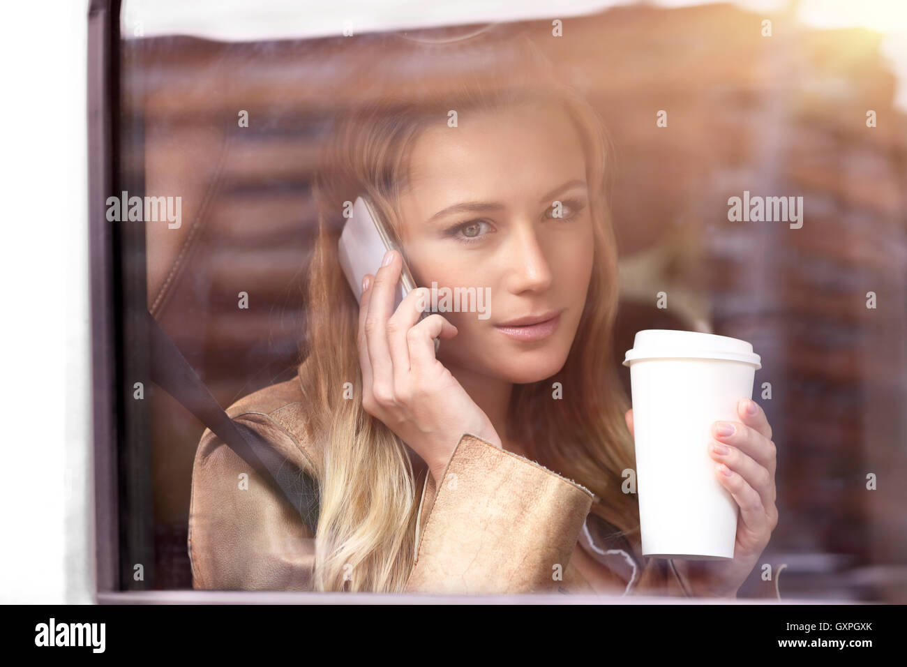 Porträt einer schönen Geschäftsfrau sitzen im Auto mit Tasse Kaffee, sprechen am Telefon Stockfoto