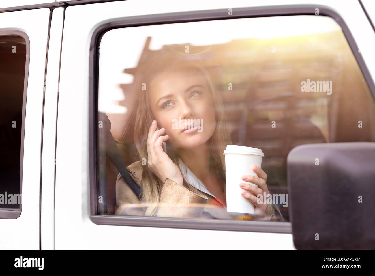 Porträt einer schönen Ernst Frau Kaffeetrinken im Auto, zur Arbeit zu gehen und am Telefon sprechen Stockfoto