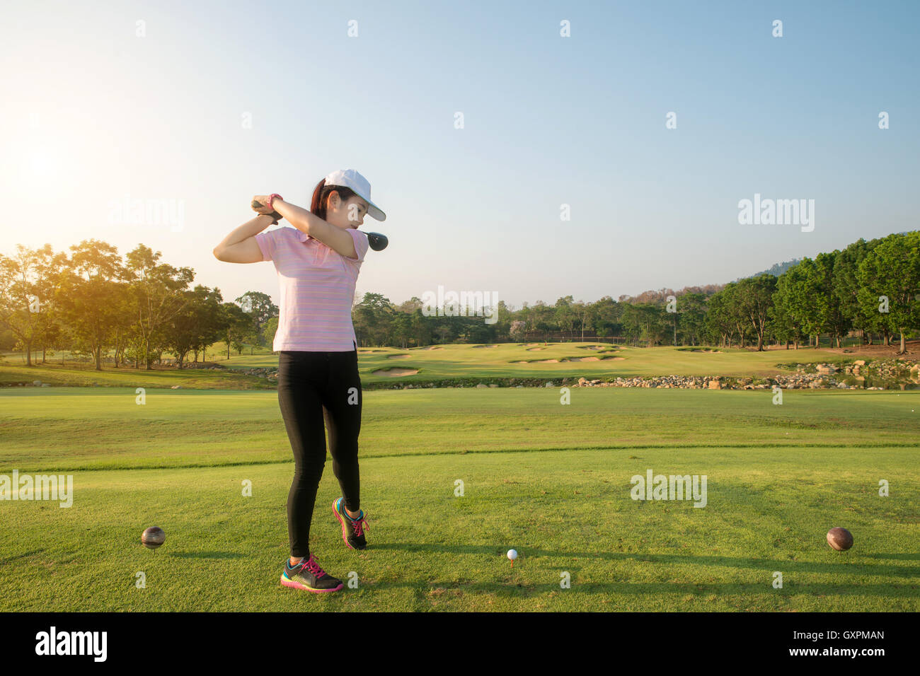 Asiatische Frau Golf hit weitläufigen Golfplatz im Sommer. Golf-Sport-Konzept. Stockfoto