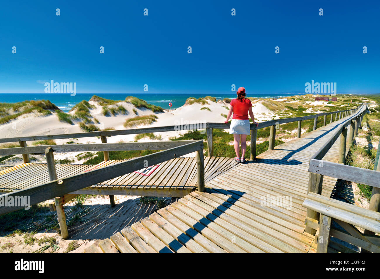 Portugal: Frau genießen Sie Strand und Meer Blick auf einem hölzernen Wanderweg in Praia de Comporta Stockfoto