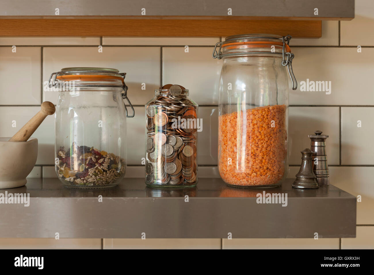 Gläser von Münzen und Zutaten auf Küchenregal Stockfoto