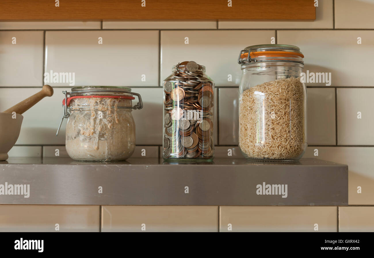 Gläser auf Küchenregal mit Zutaten und Münzen Stockfoto