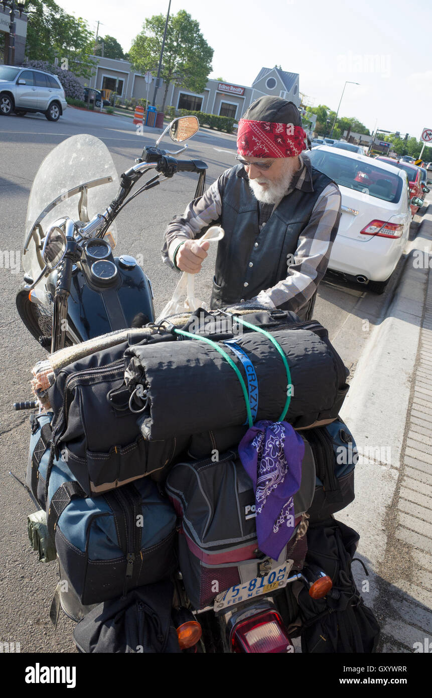 Ältere Gentleman Verpackung Motorrad für die Straße mit Vorräten, die Antizipation einer Outdoor-camping-Ausflug. St Paul Minnesota MN USA Stockfoto