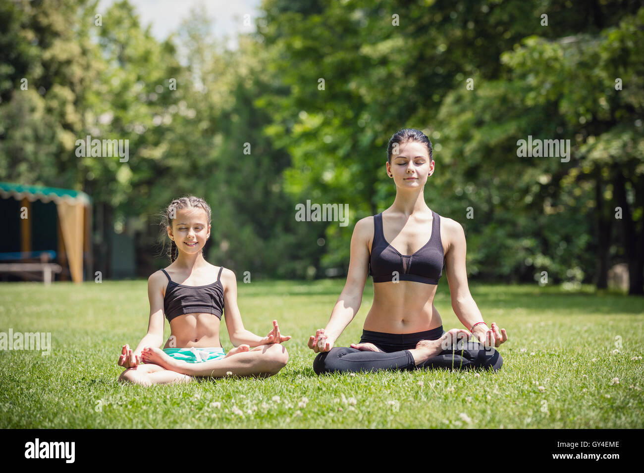 Junge Mutter und Tochter üben im park Stockfoto