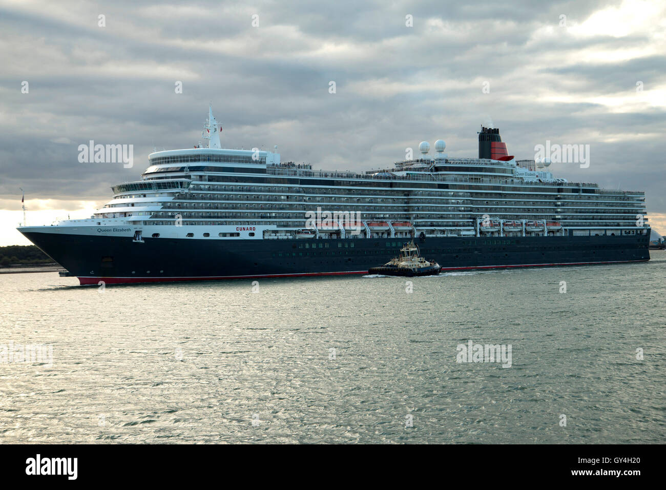 Cunard Cruise Schiff Queen Elizabeth verlassen Southampton auf dem Weg nach Lissabon am 16. September 2016 mit einem Schlepper neben Stockfoto
