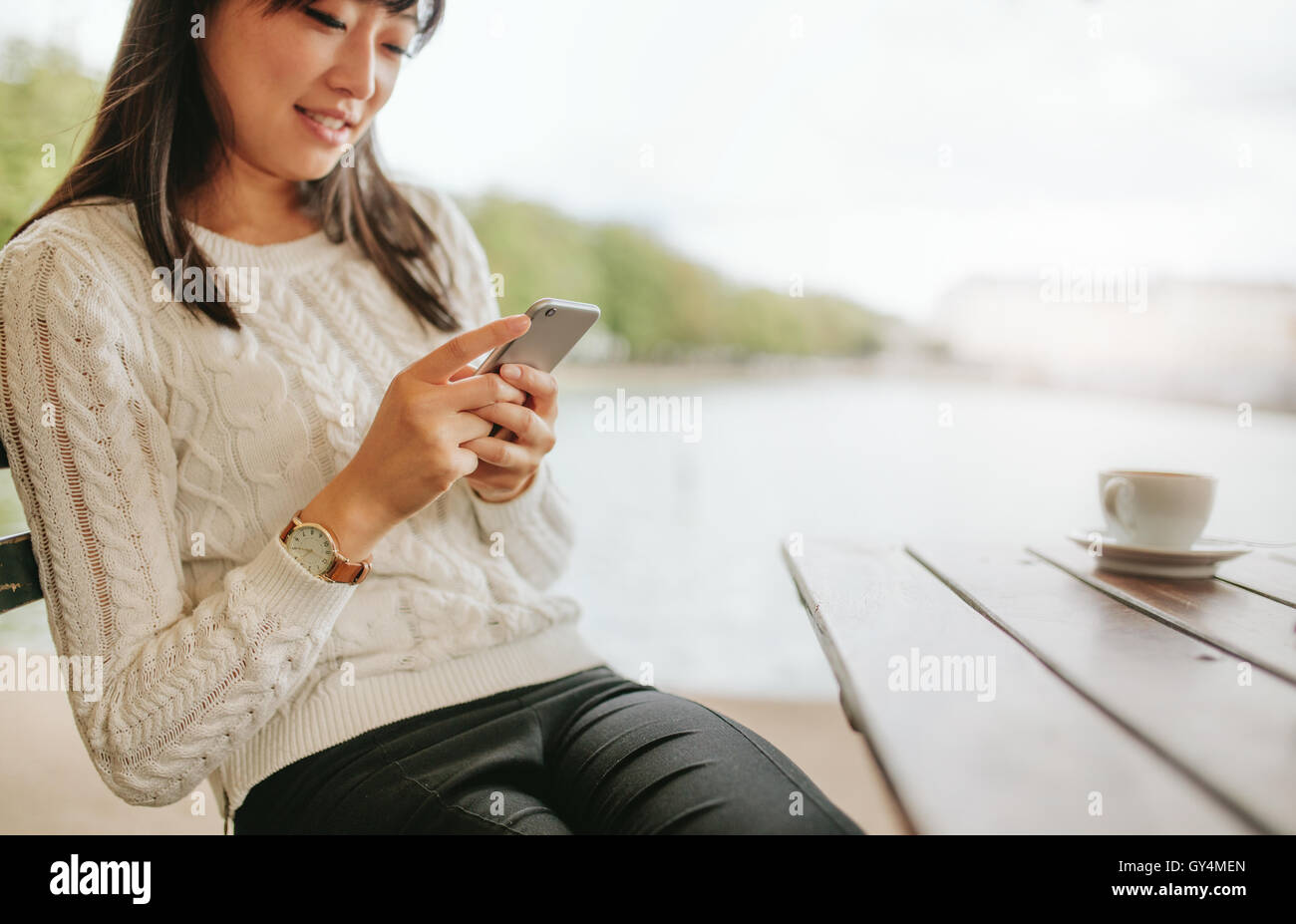 Schuss der hübsche junge Frau mit Handy im Café. Junge Frau sitzt am Kaffeetisch im freien lesen SMS auf h Stockfoto