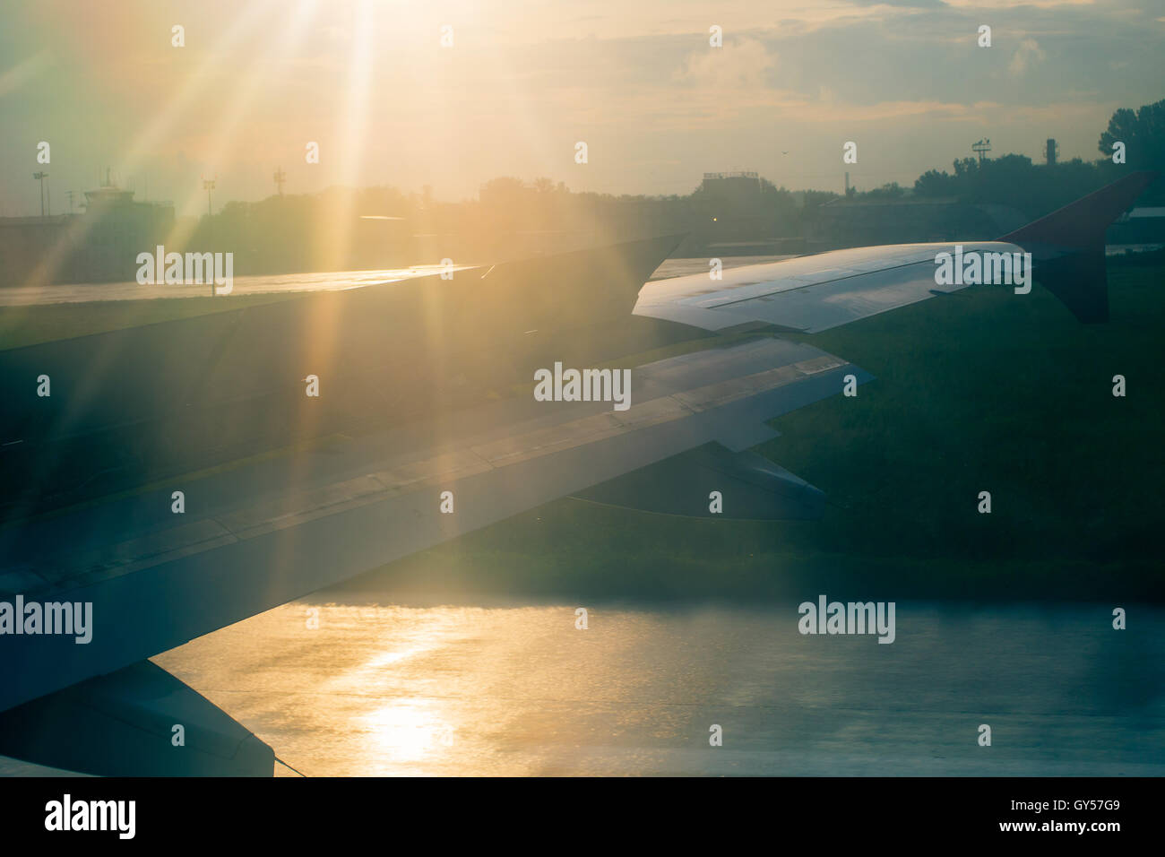 Flugzeugflügel in Sonnenstrahlen bei der Landung. Am frühen Morgen Stockfoto