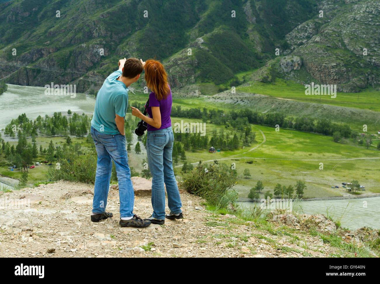 Junges Paar (kaukasischer Mann und Frau) unter der Natur Blick auf die schöne Landschaft mit Bergen, die etwas zeigen Stockfoto