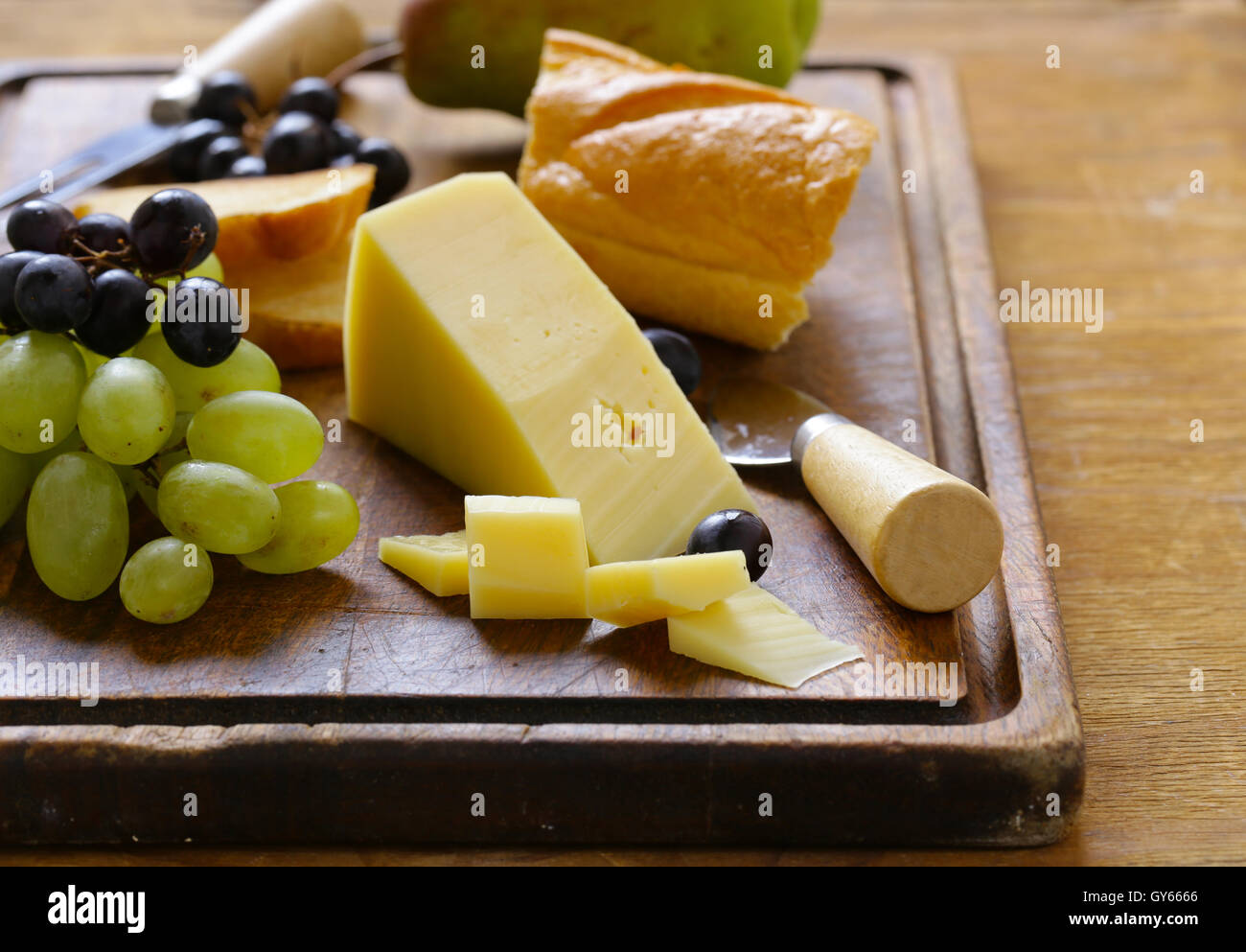 Käse vom Brett mit Trauben, Birnen und baguette Stockfoto