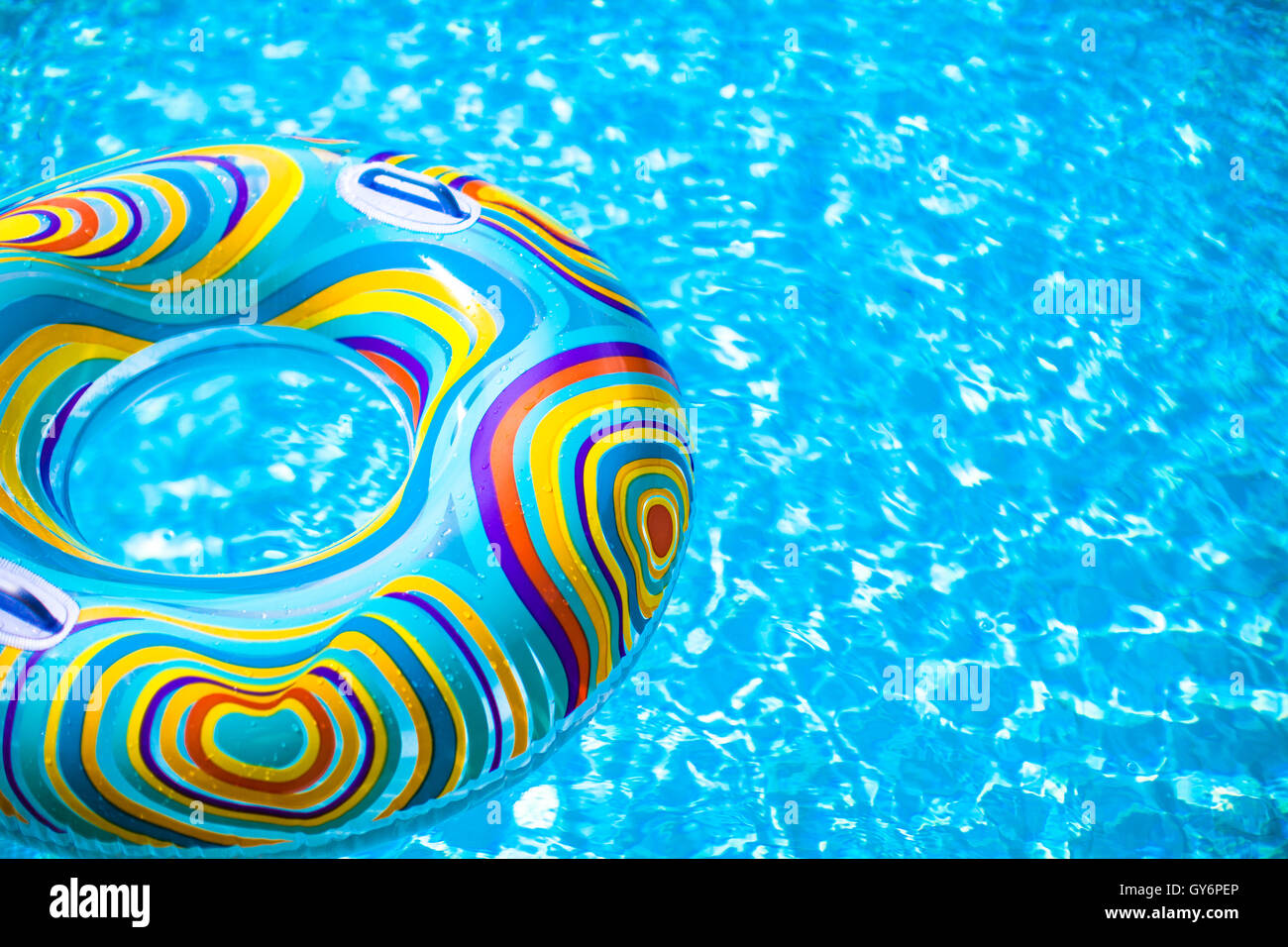 Aufblasbare bunte Gummiring schwebend in blauen Swimmingpool Stockfoto