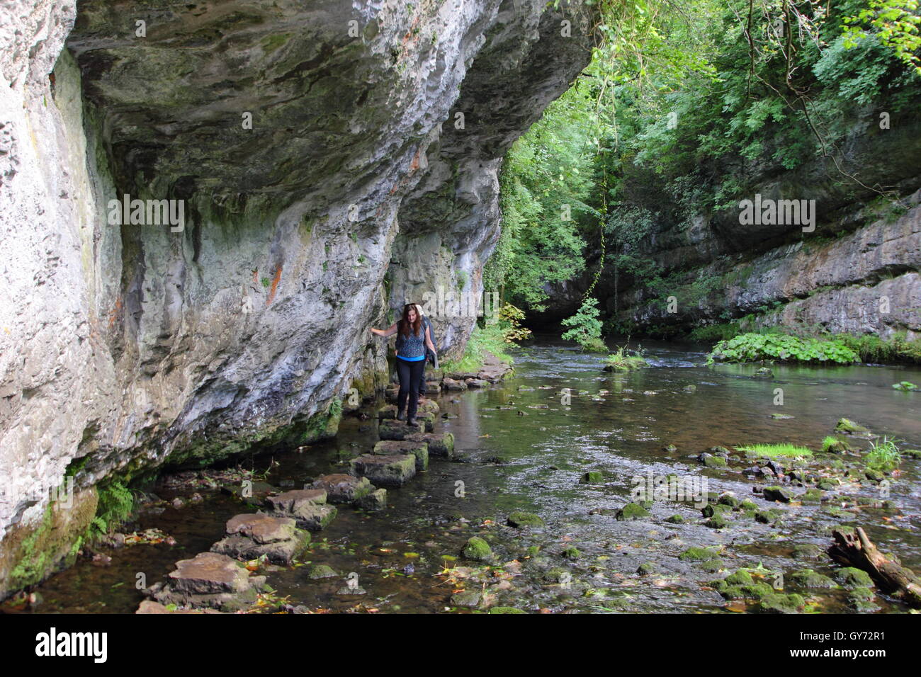 Wanderer durchqueren Trittsteine entlang des Flusses Wye in Chee Dale, einer spektakulären Kalkstein-Schlucht, Peak District NP, Derbyshire, UK Stockfoto