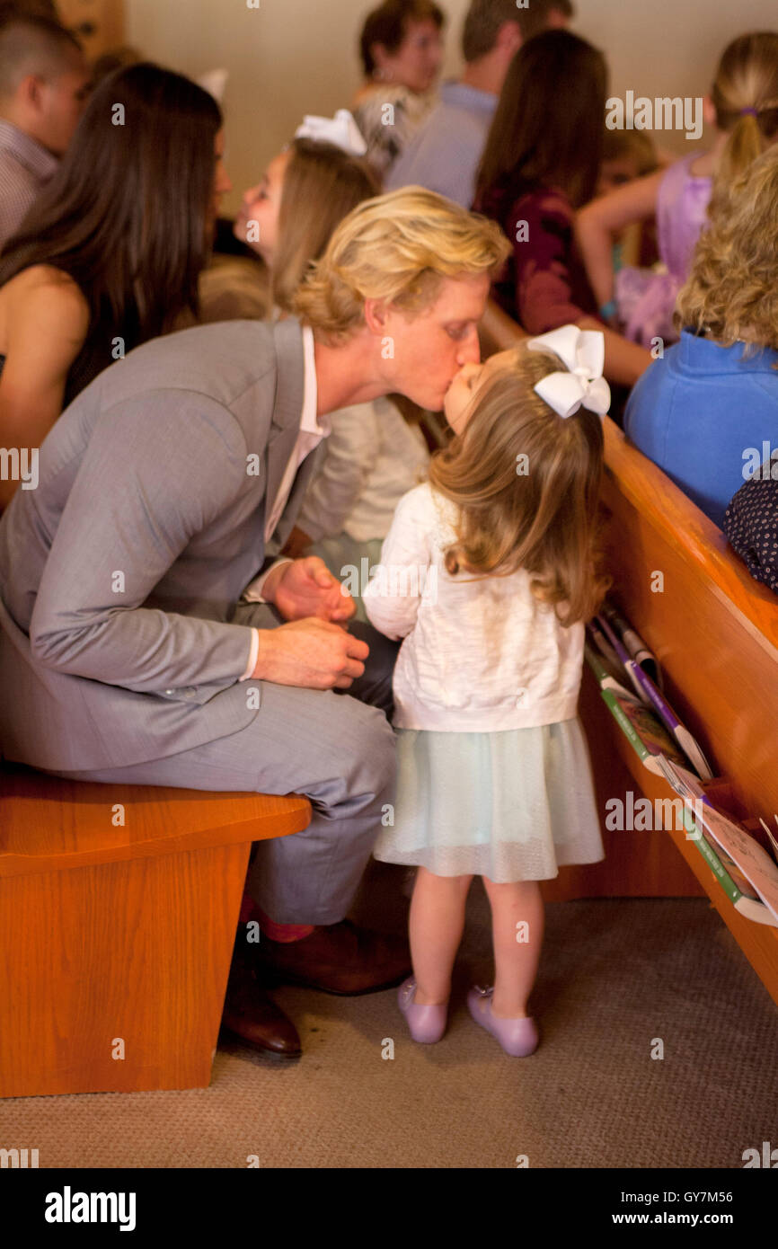 Ein kleines Mädchen küsst ihr Vater liebevoll in eine Kirchenbank während der Gottesdienste in der Kirche eine Laguna Niguel, CA. Stockfoto