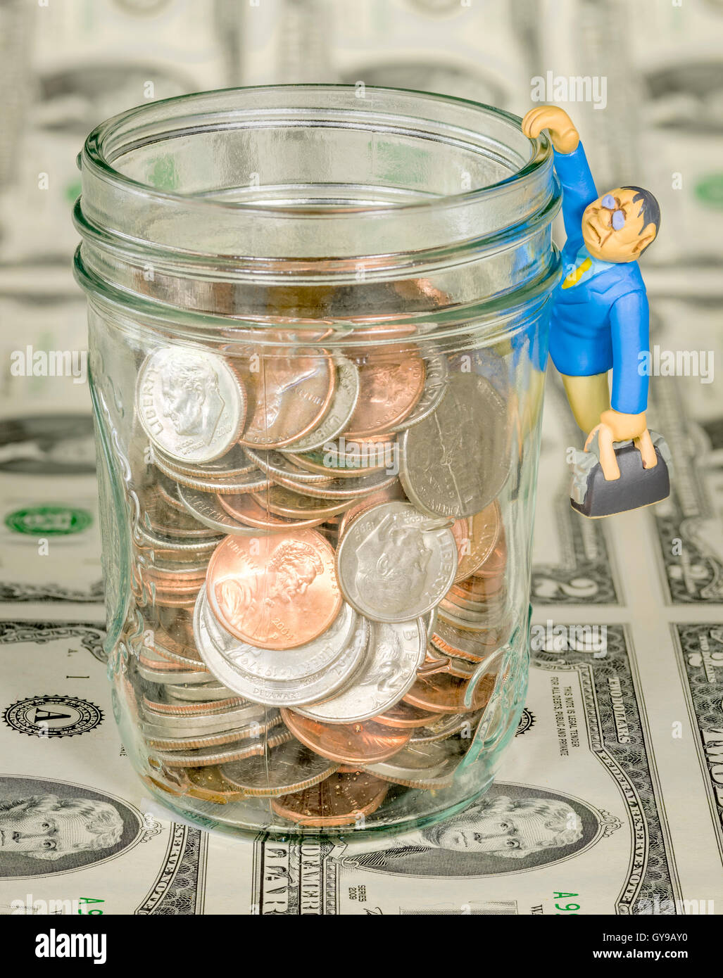 Geld in ein Glas und Papier mit einem Spielzeug Mann mit Aktentasche Stockfoto