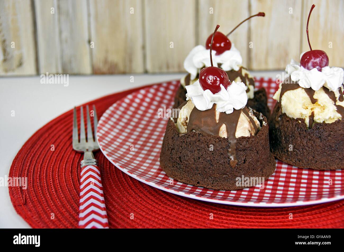 Eisbecher mit Fudge Sauce in Brownie Schüssel auf rot-weiß karierte Teller Stockfoto