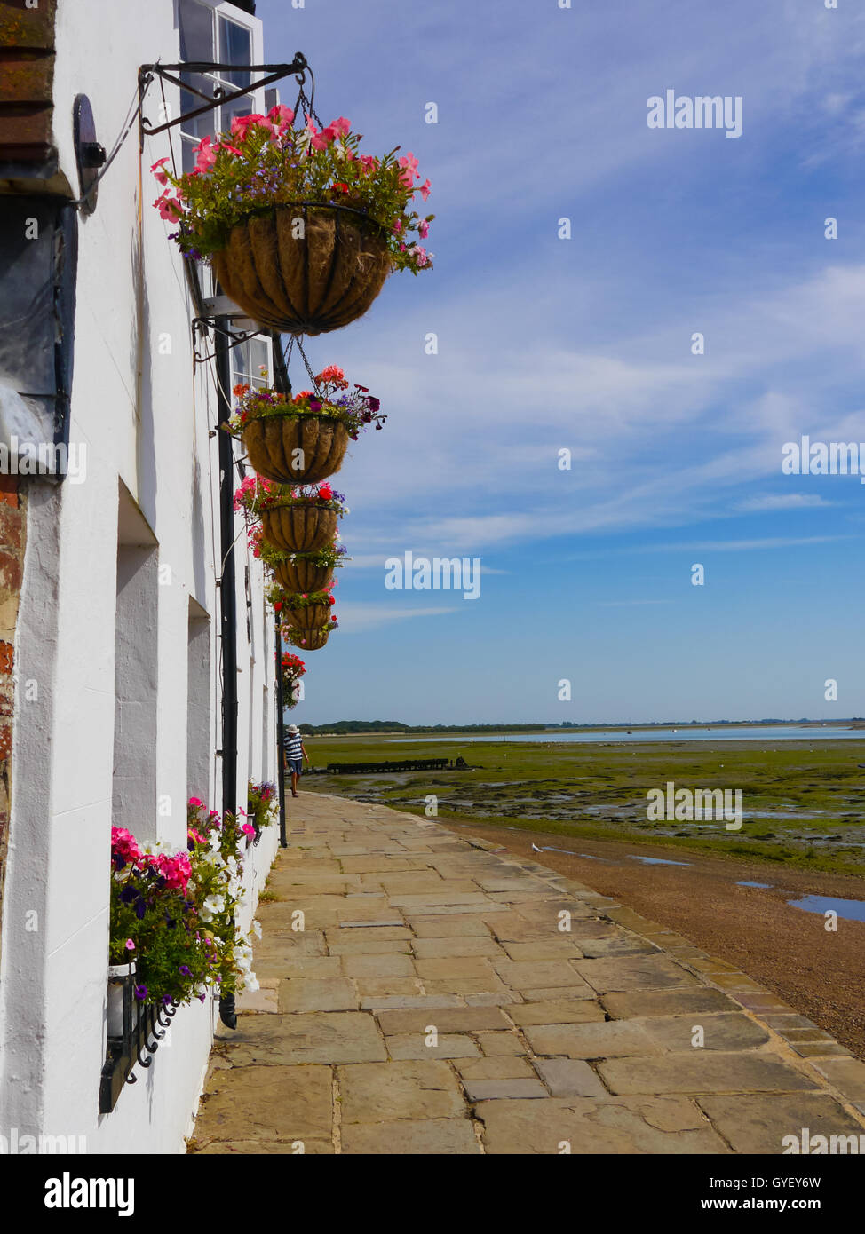 weiße Häuschen mit hängenden Blumenkörben entlang der Küste von Langstone High Street, Hampshire, England Stockfoto