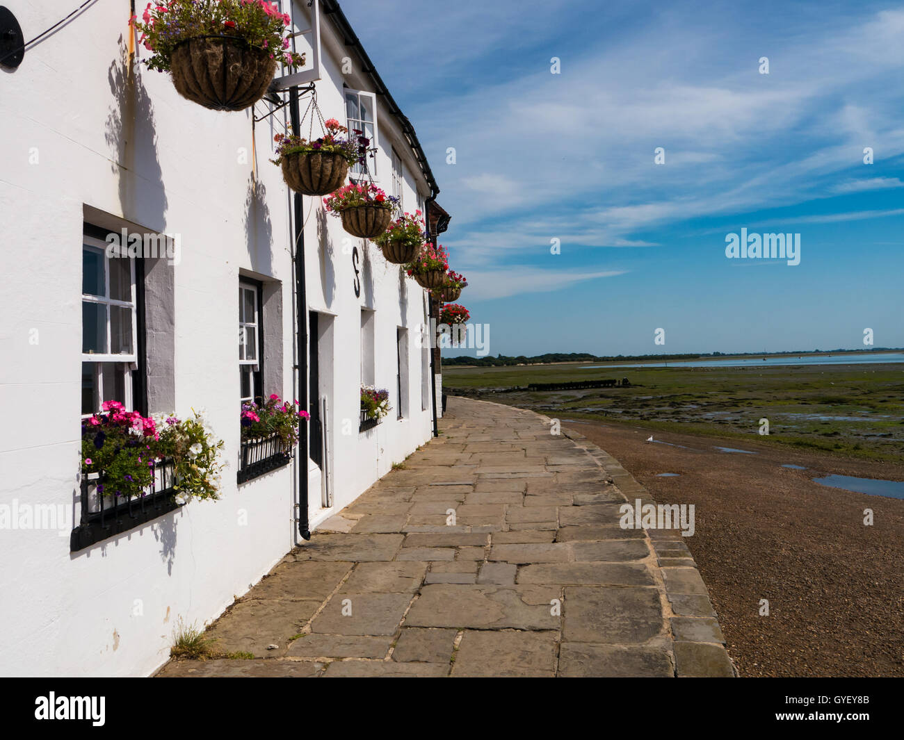 weiße Häuschen mit hängenden Blumenkörben entlang der Küste von Langstone High Street, Hampshire, England Stockfoto