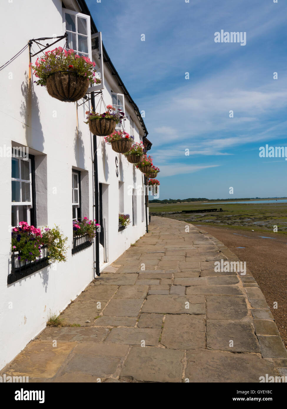 weiße Häuschen mit hängenden Blumenkörben entlang der Küste von Langstone High Street, Hampshire, England Stockfoto