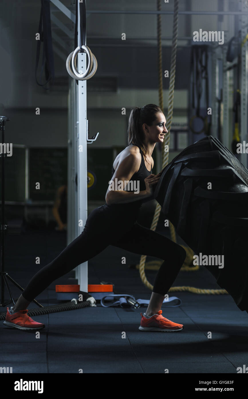Konzept: Kraft, Stärke, Gesundheit, Sport. Leistungsstarke attraktive muskulöse Frau CrossFit Trainer dabei riesige Reifen Training Stockfoto