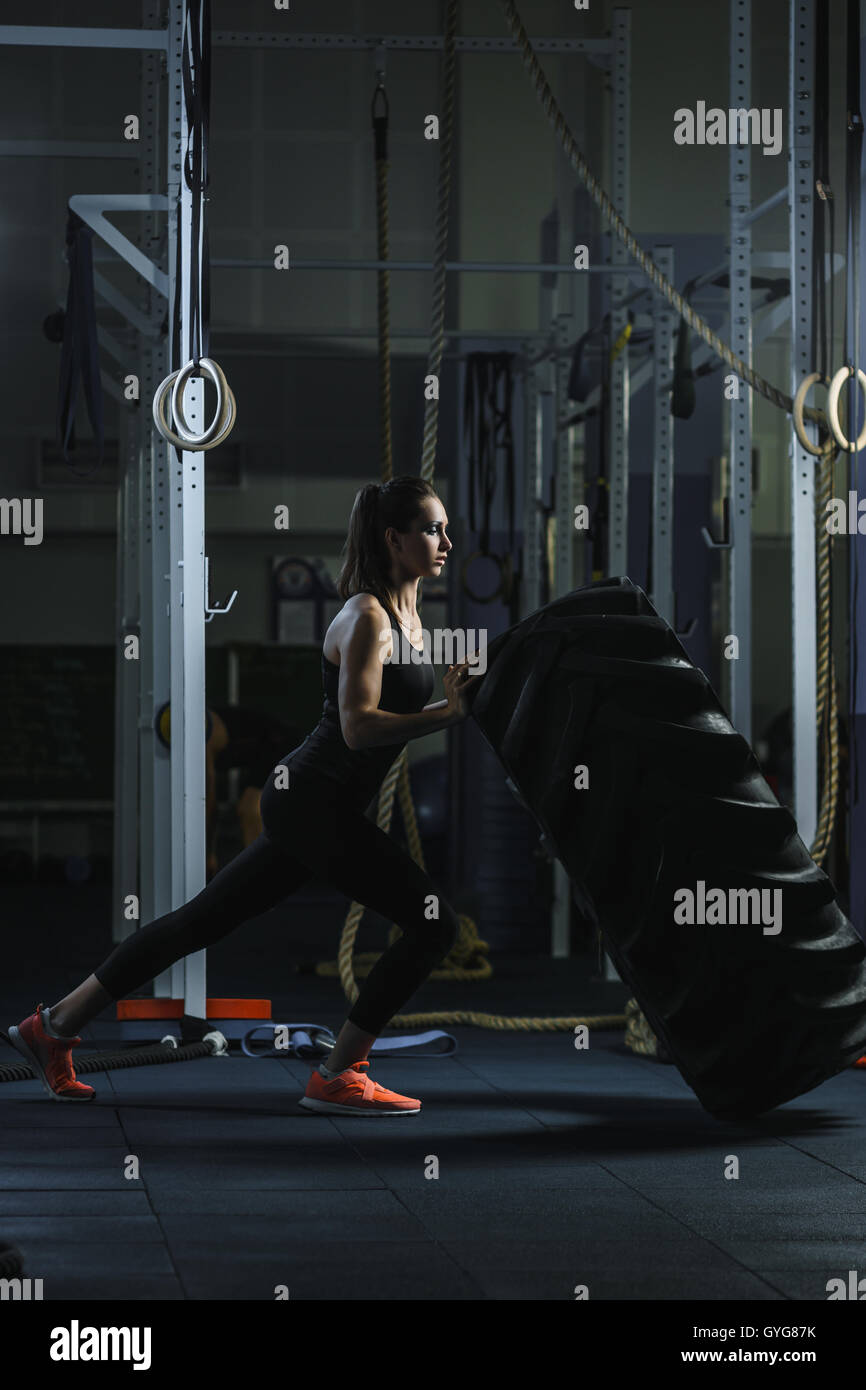 Konzept: Kraft, Stärke, Gesundheit, Sport. Leistungsstarke attraktive muskulöse Frau CrossFit Trainer dabei riesige Reifen Training Stockfoto