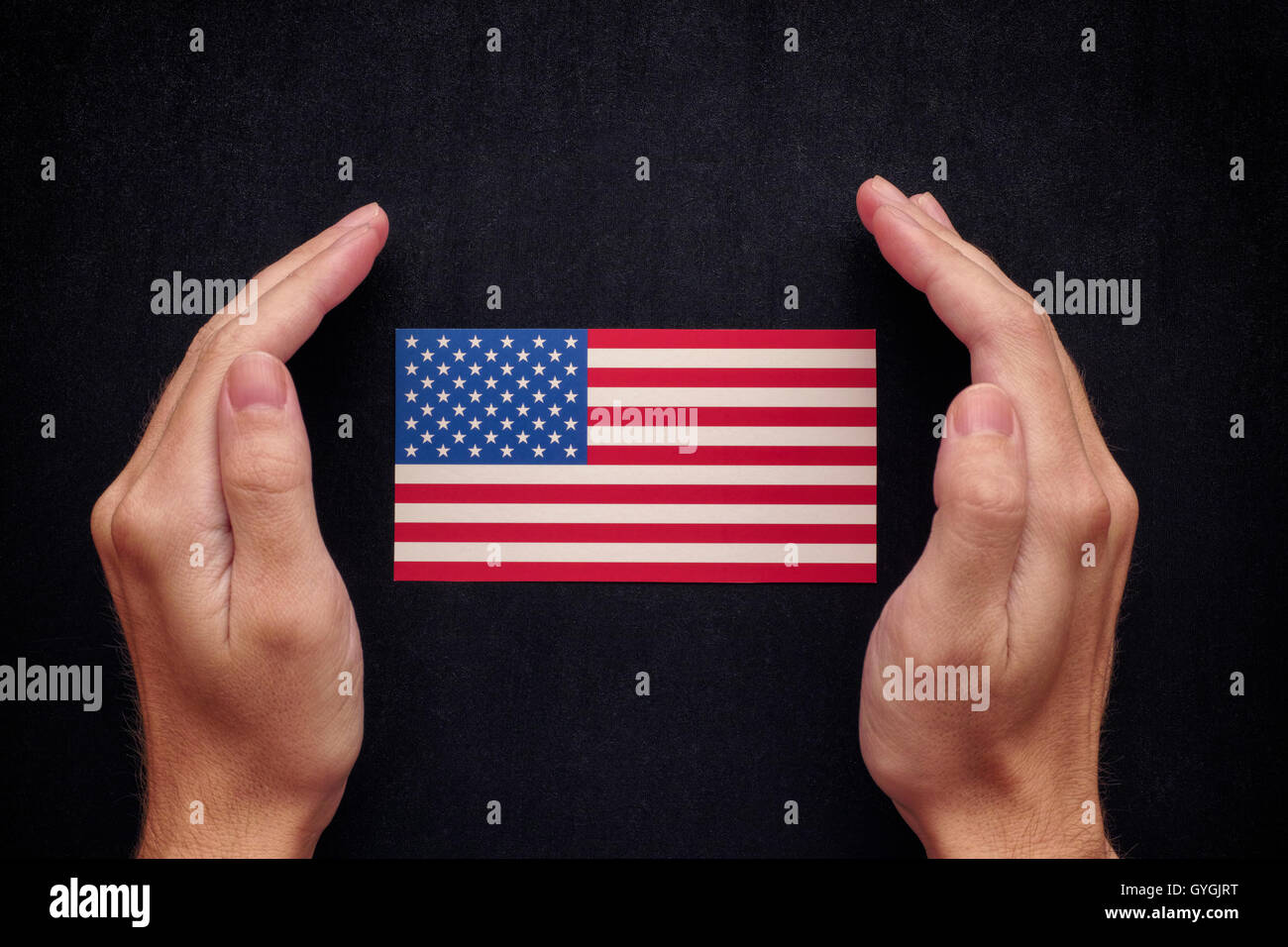 Hände, die Usa-Flagge auf schwarze Tafel Hintergrund zu schützen. Hautnah. Stockfoto
