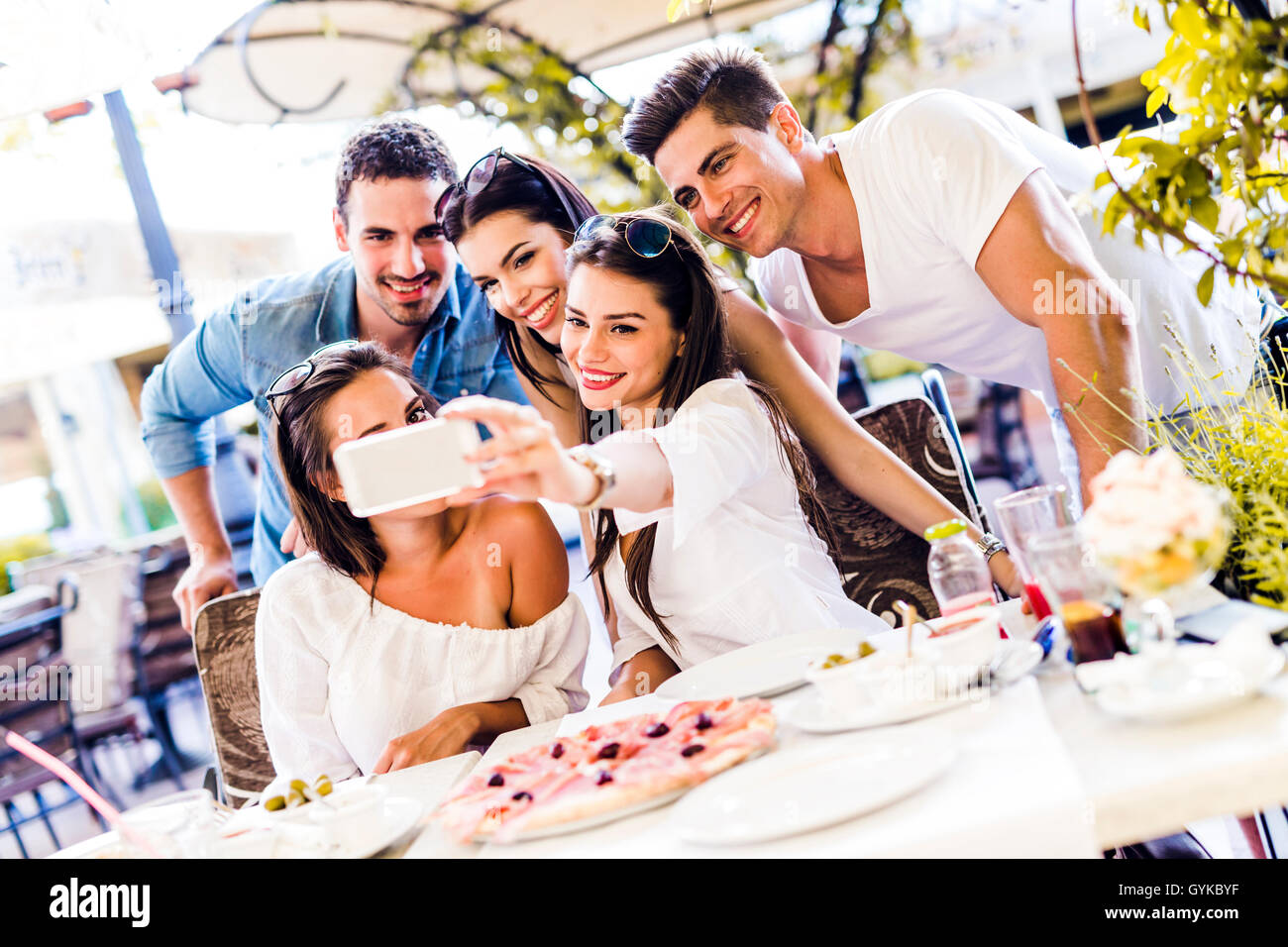 Gruppe von schönen Jugendlichen in einem Restaurant sitzen und dabei das Lächeln auf den Lippen eine selfie Stockfoto