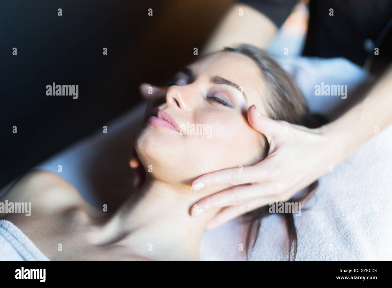 Behandlung von Gesicht, eine schöne, junge Frau auf der Massagebank liegen Masseur Stockfoto